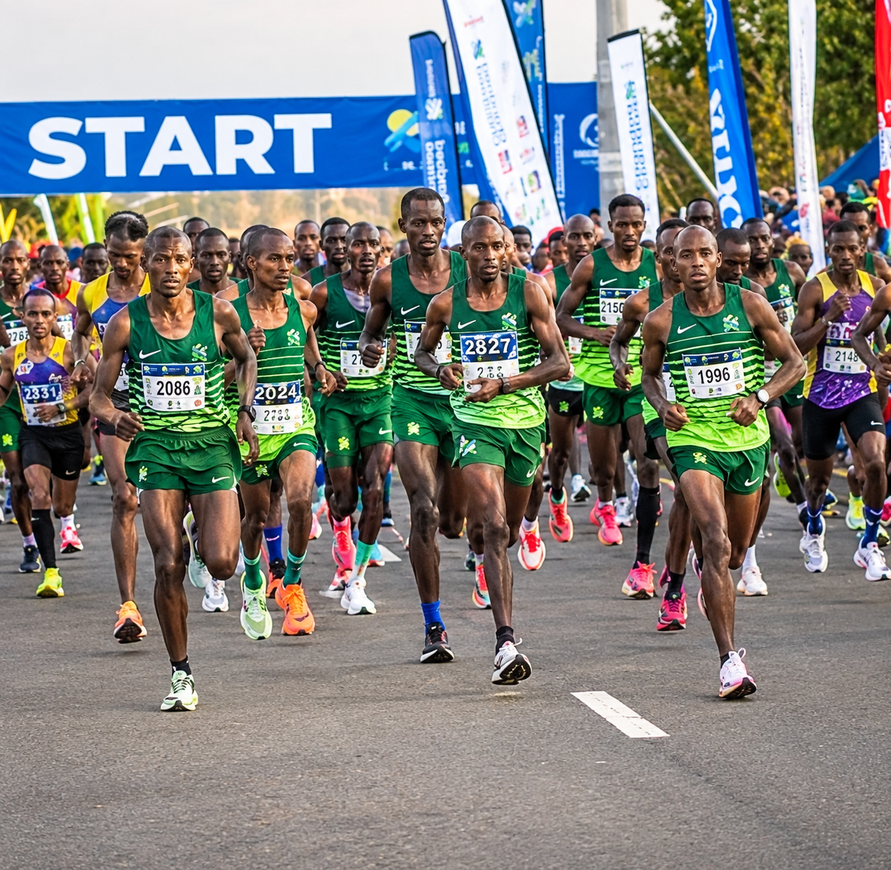 Lead pack of runners in green kit setting off from the marathon start line